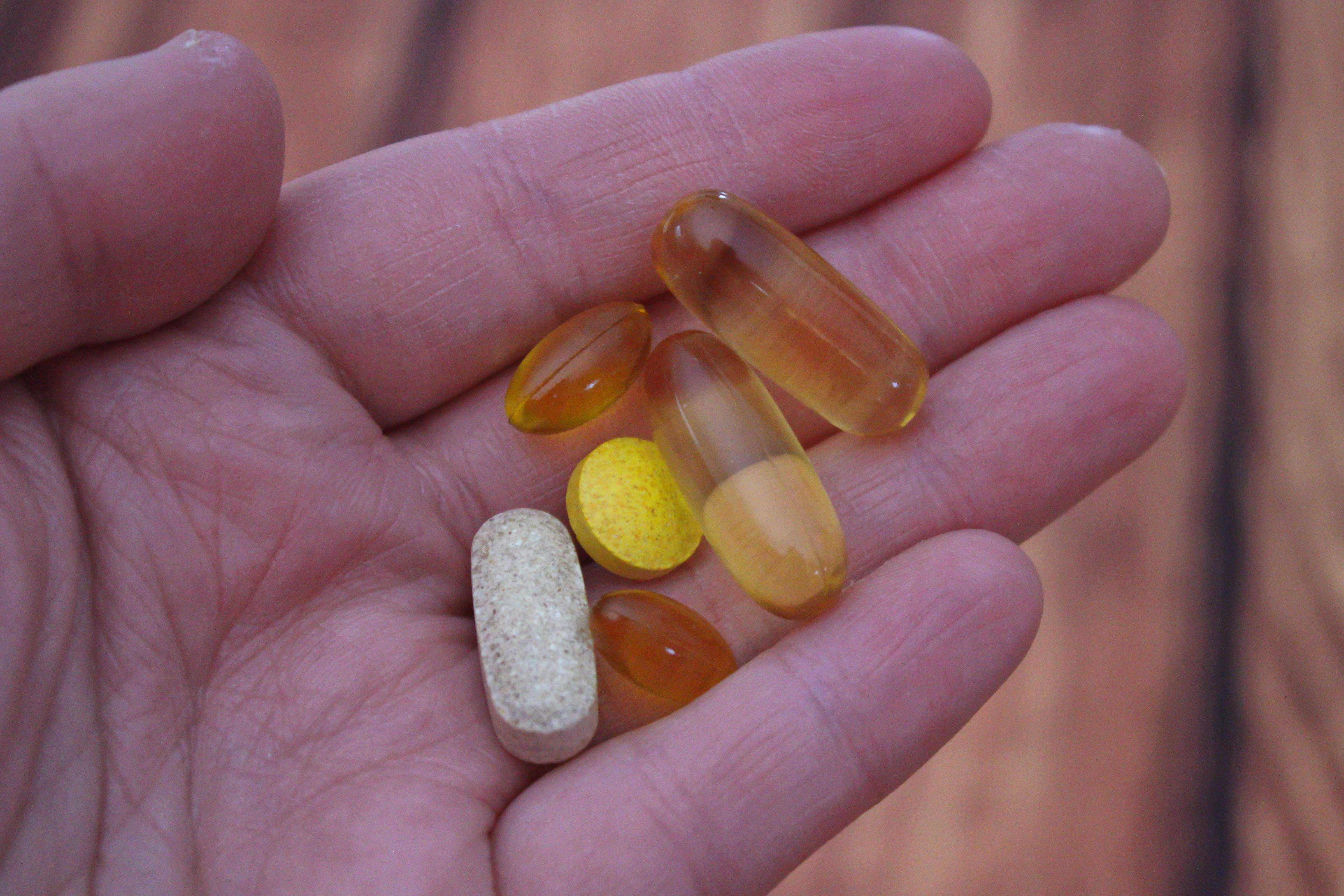 Open hand holding various vitamins and supplements